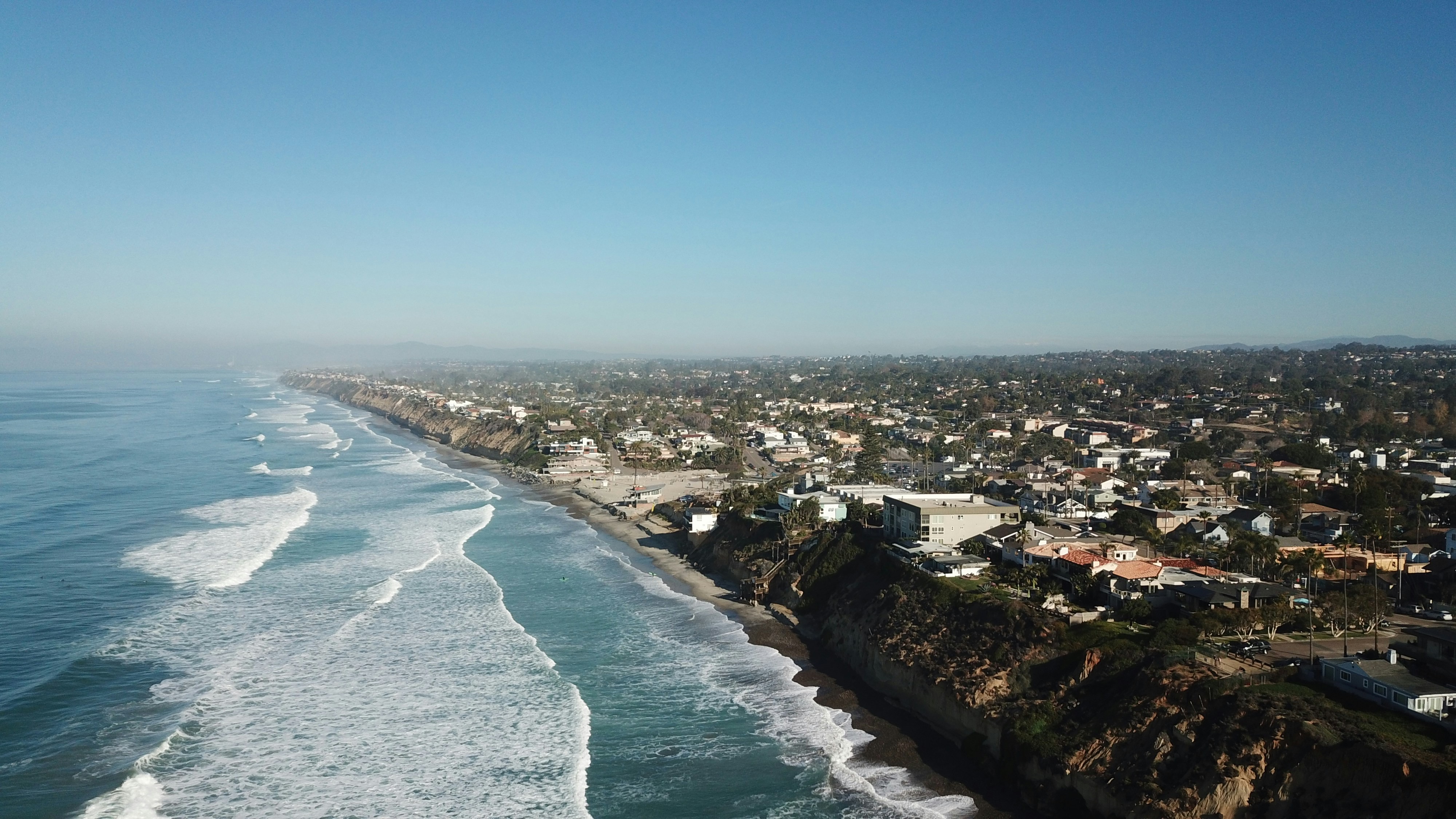 Aerial view of the Encinitas coastline — bluffs, beach, and neighborhoods stretching north